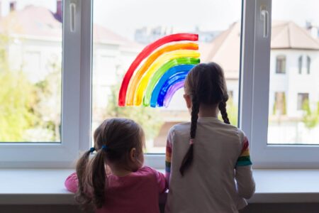 Was bringen Ausgangssperren? Kinder blicken aus dem Fenster